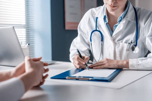 doctor sitting at desk and writing a prescription for her patient